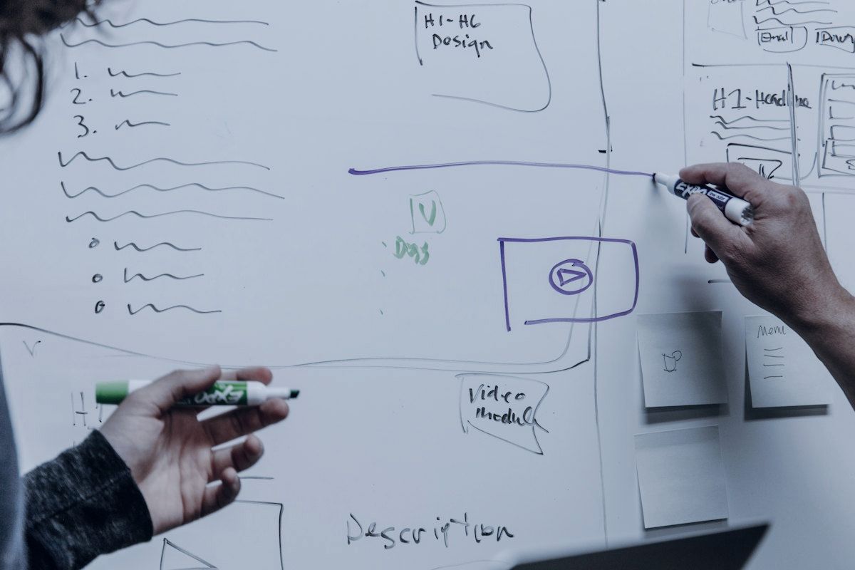 Two people sketching a system diagram on a whiteboard.